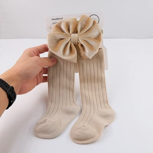 Detail of velvet bow headband and ribbed cotton long socks set for infants in beige
