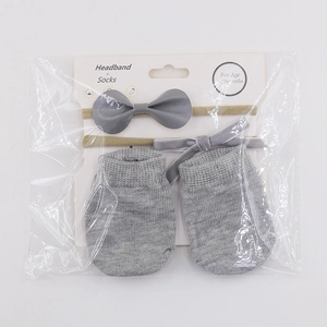 Baby gift set with grey leather bow headband and matching knit socks in retail packaging