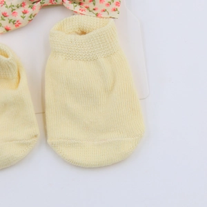 Detailed view of light yellow knitted baby socks with floral bow accessory