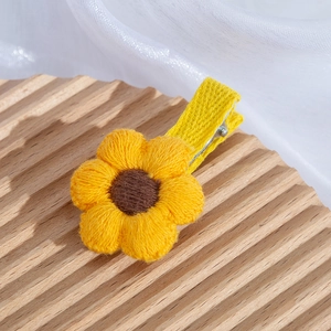 Close-up of yellow crochet sunflower hair clip with ribbon-wrapped metal crocodile clip