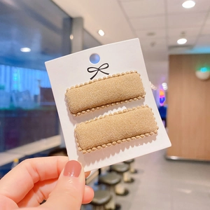 Detail of khaki faux cashmere rectangular BB hair clips with pom-pom wavy edge trim