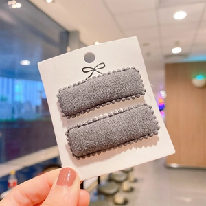 Close-up of grey cashmere-like rectangular BB hair clips with wavy edges on a card