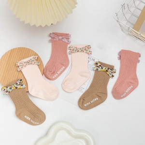 Close-up of ribbed cotton baby socks with floral bows in pink and beige tones