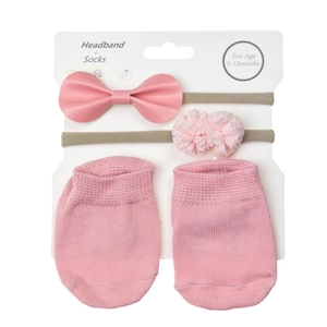 Close-up of pink baby gift set featuring lace flower headbands and knit non-slip socks