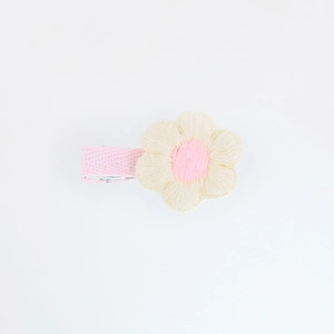 Close-up of a handmade crochet flower hair clip with pink center on a pink ribbon band
