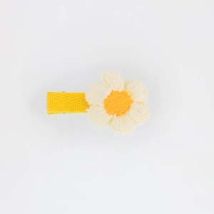 Detail of hand-woven yellow hair clip with white and orange embroidered flower petal