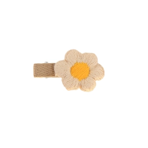 Detailed view of handmade crochet flower hair clip with soft beige and yellow yarn texture