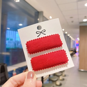 Close-up of vibrant red knit wool BB hair clips with wavy edges on a display card