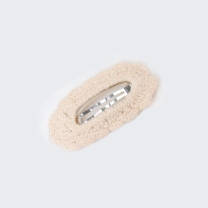 Detailed close-up of knitted cotton lace hair clip with scalloped beige edges