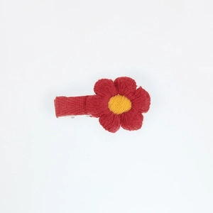 Detailed macro view of a red knitted flower hair clip with yellow center and fabric wrap