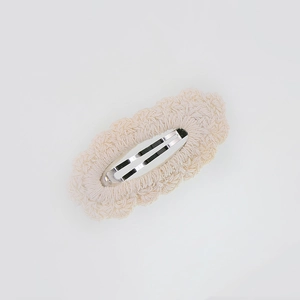 Detailed view of cream white crochet lace knit fabric on a metal BB hair clip