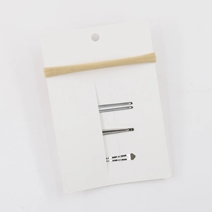 Close-up of khaki elastic hair tie and three silver metal clips on a display card