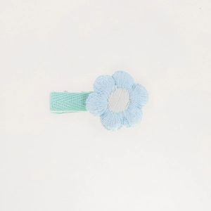 Detail of hand-knitted light blue flower hair clip with white center for girls