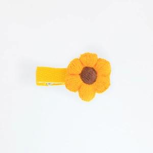 Detailed macro view of handcrafted knitted sunflower hair clip with yellow petals