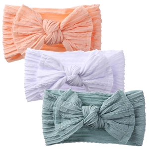 Three-piece baby cable knit headbands with large bows in soft pastel pink, white and blue