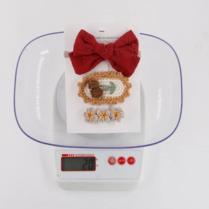 Three-piece handmade knitted floral hair clip set on a white card for weight checking