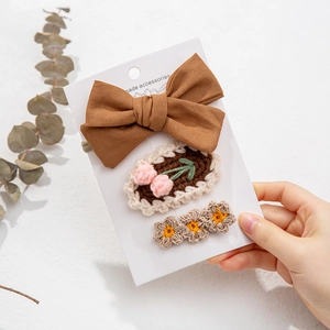 Detailed set of three handmade knit flower and bow hair clips on a white display card
