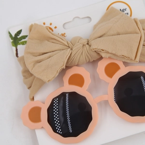 Baby accessory set featuring beige bow headband and pink flower sunglasses on display card