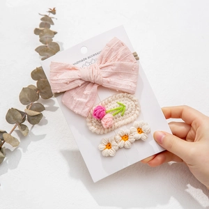 Three-piece handmade knitted hair clips including floral and bow designs on a display card