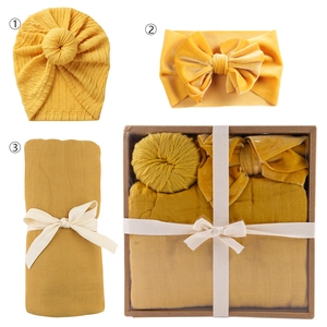 Newborn baby gift set featuring mustard yellow swaddle blanket, knot hat and velvet bow headband