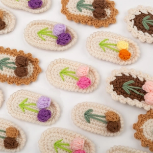 Handmade crochet flower and cherry hair clips in soft pastel colors on white background