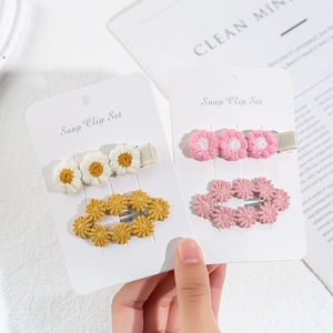 Detailed close-up of embroidered daisy and pink floral snap clip set for children