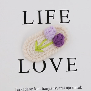 Detail of handmade crochet tulip hair clip with purple flowers and green leaves