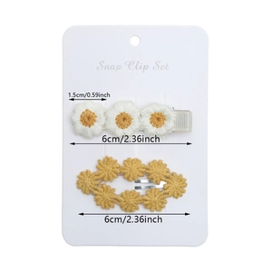 Detail of white daisy embroidery and yellow lace snap clips for toddlers on a display card