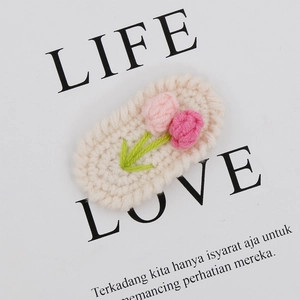 Detail showing handmade crochet tulip hair clip with pink flowers and knit textures