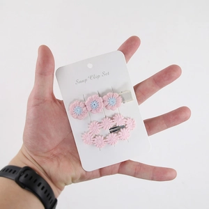 Detail of pink embroidered daisy hair clips for kids on a branded white display card