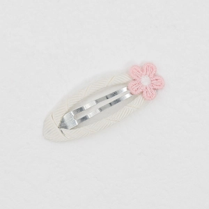 Detail einer süßen Baby-Haarklammer mit rosa gesticktem Gänseblümchen auf weißem Band