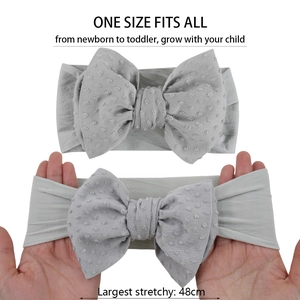 Vue détaillée d'un bandeau gris pour bébé avec nœud à pois montrant l'élasticité élevée
