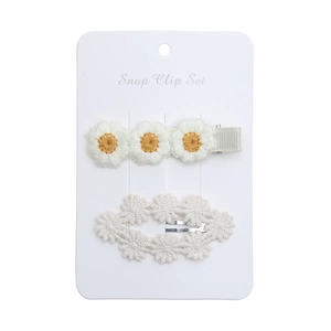 Detail view of white embroidered daisy and lace snap clips on white card holder