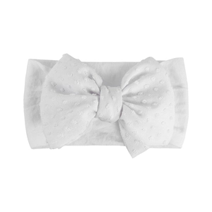 Détail du bandeau bébé blanc avec grand nœud et texture de tissu jacquard à pois doux