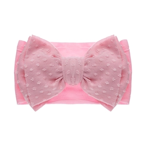 Détail du bandeau bébé rose en nylon avec un grand nœud à motif de pois texturé
