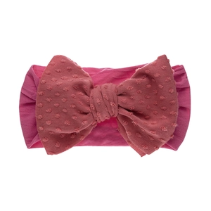 Détail du bandeau bébé rose avec un grand nœud en tissu jacquard à pois