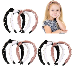 Close-up of velvet pearl headbands in black, white, and pink with a stylish knot design