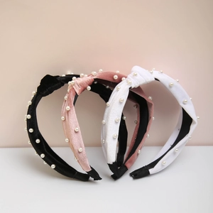 Close-up of velvet knot headbands in black, pink and white with imitation pearl beading