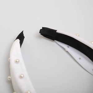 Detail of white velvet headband with pearl beads showing secure black ribbon end finish