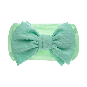 Détail du bandeau bébé vert clair avec tissu côtelé et gros nœud à pois blancs