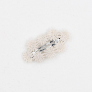 Detail einer Baby-Haarklammer mit weißer Häkel-Gänseblümchen-Blume auf Silber-Clip