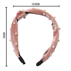 Pink velvet padded headband with white pearls and knot design on a white background
