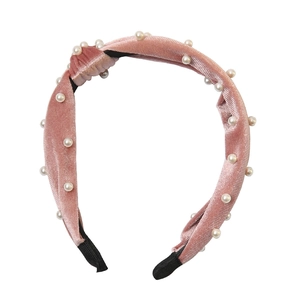 Detail shot of pink velvet headband with elegant pearls and a stylish top knot design