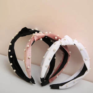 Three velvet knotted headbands with pearl accents in black, nude pink, and white colors
