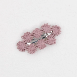 Detail der handgestrickten Blumenhaarklammer in Altrosa mit silbernem Metallschnabelclip