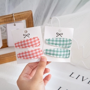 Detailed view of red and green plaid BB hair clips for babies in a 2-piece set display
