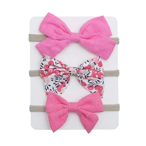 Close-up of three different bow headbands including floral and pink fabric styles