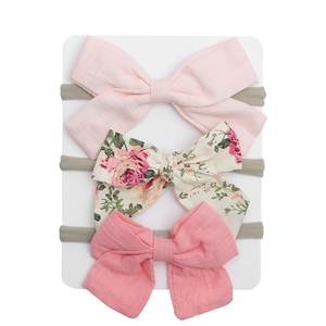 Detailed macro view of three fabric bow headbands with floral prints and solid colors
