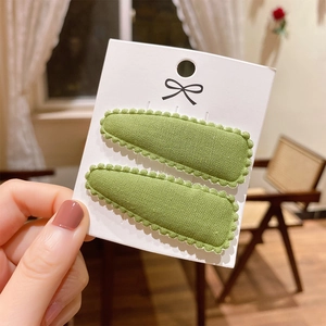 Close-up of green cotton lace-edged hair clips for kids on a white display card