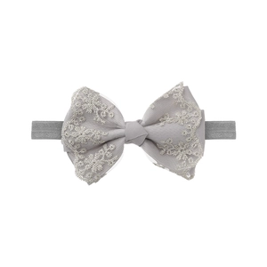 Detail of baby elastic headband featuring grey double-layered lace bow and floral embroidery